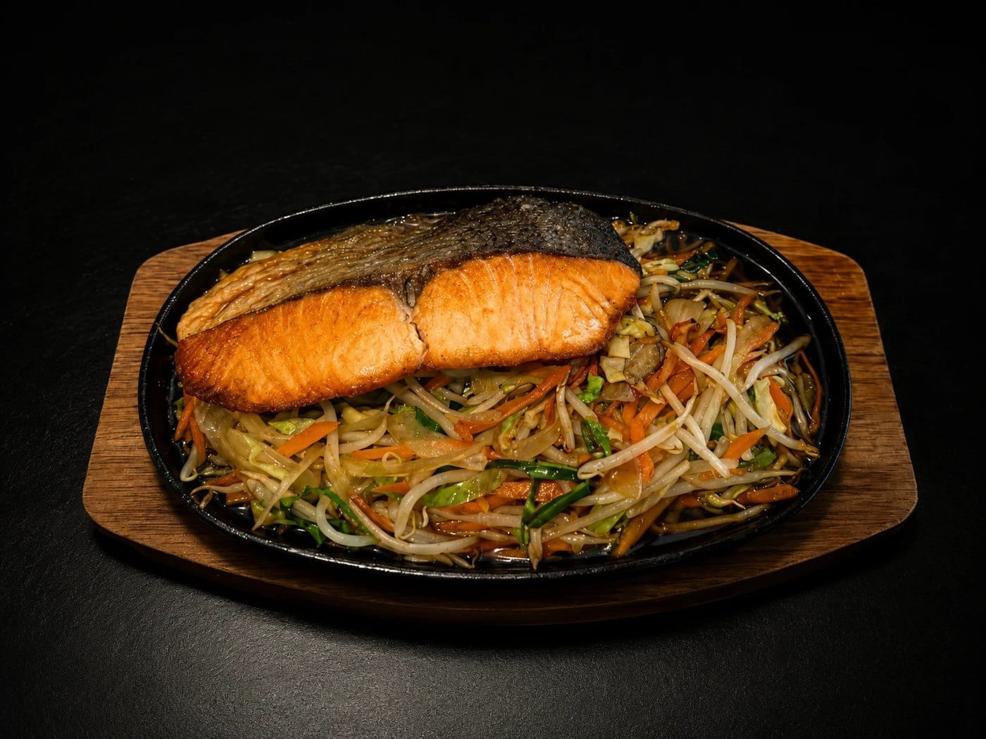 Salmon teriyaki on a sizzling iron plate with beansprouts and vegetables